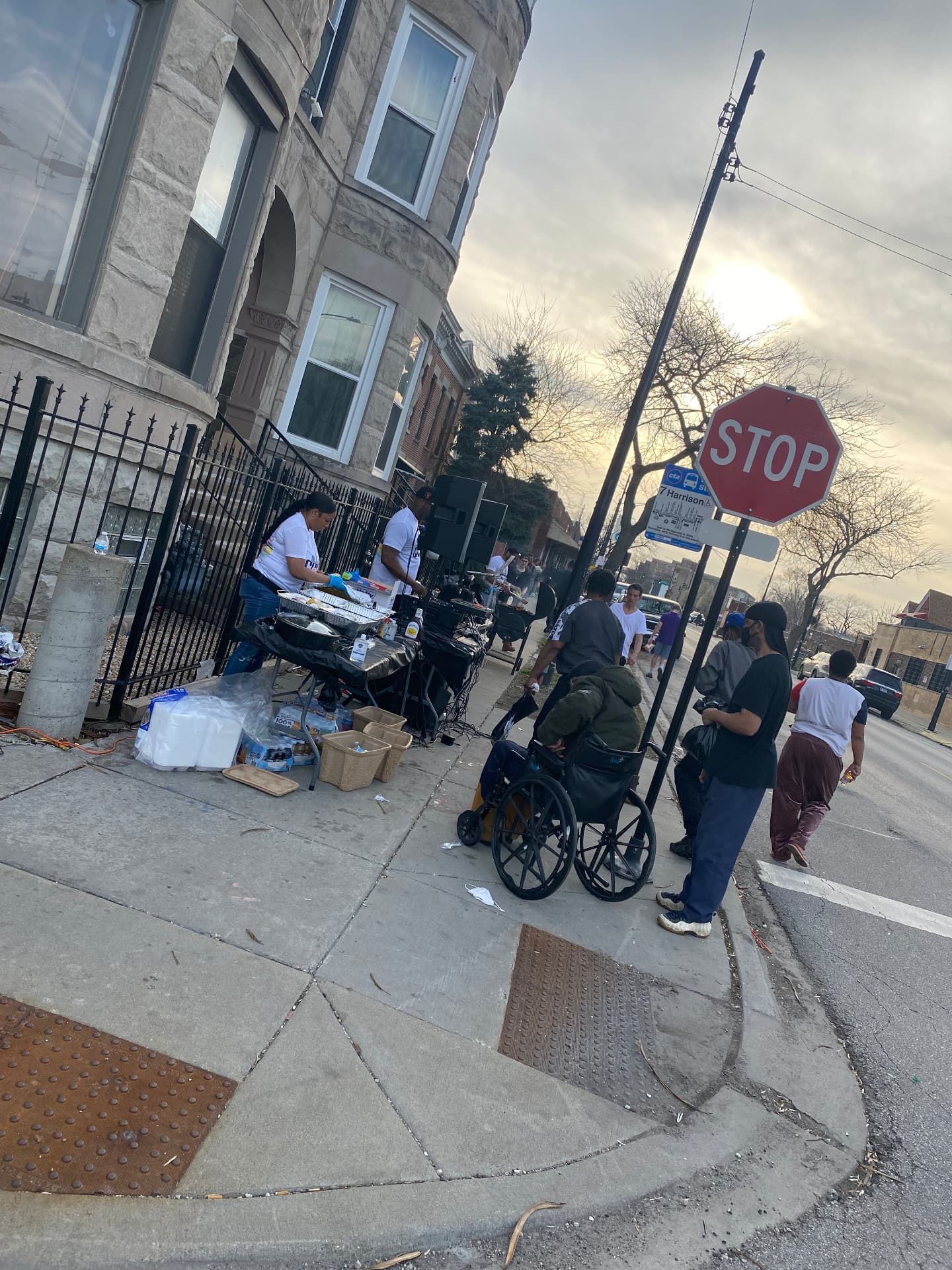 Volunteers serving hot meals from a sidewalk table at a street giveback